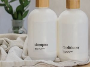 white bottles of shampoo and conditioner with a towel