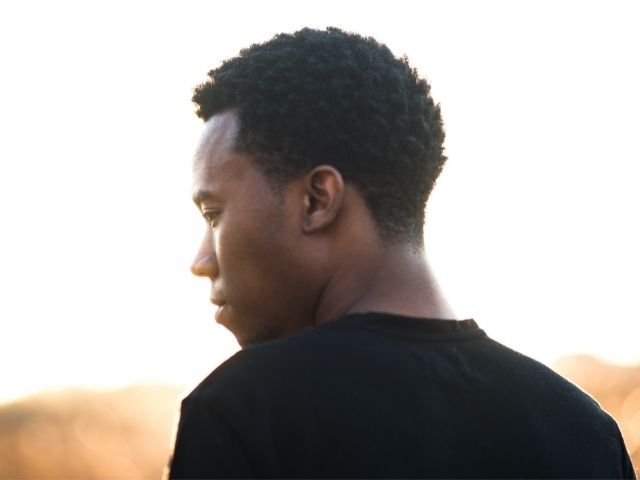 black man in black shirt standing on a sunny morning