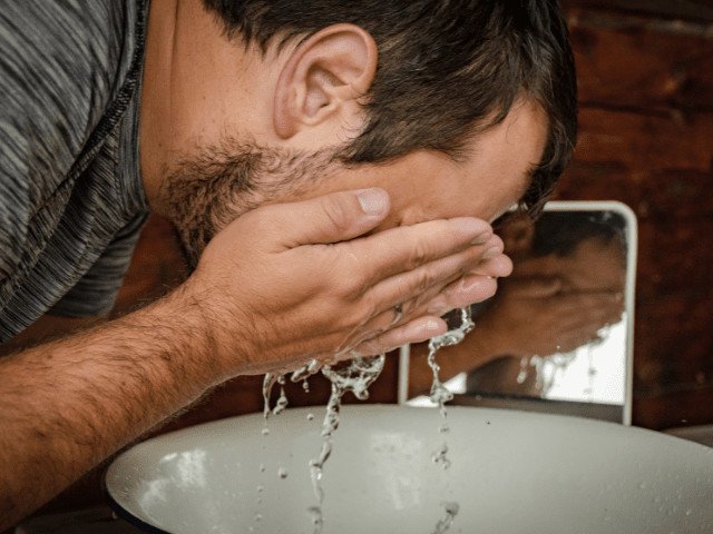 man washing his beard with water