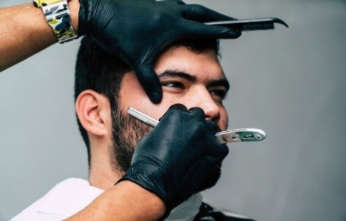 Barber shaving bearded man